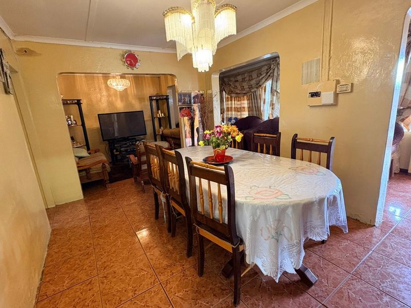 Open plan dining and living area featuring ceramic floor tiles, an archway transition, and a decorative crystal chandelier.