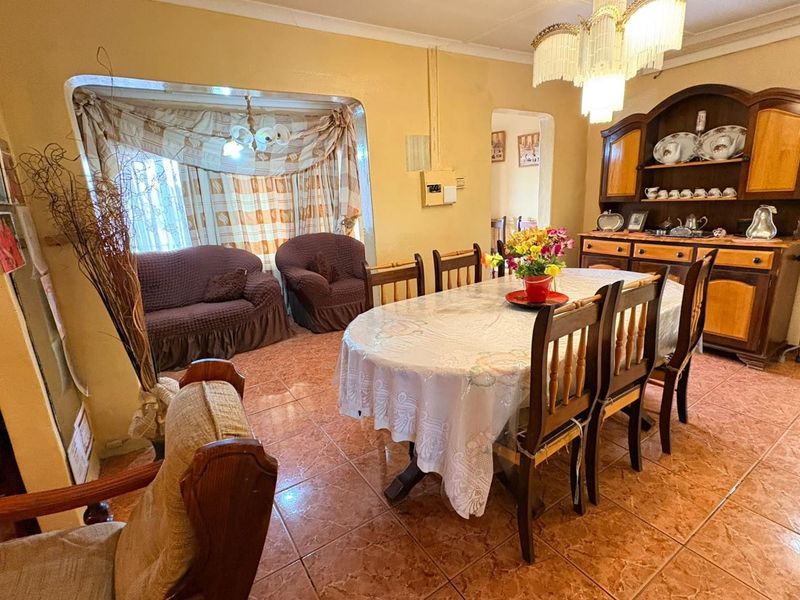 A traditional dining room featuring ceramic tile flooring, a built-in display cabinet, and a central chandelier, offering a dated aesthetic ready for modernization.
