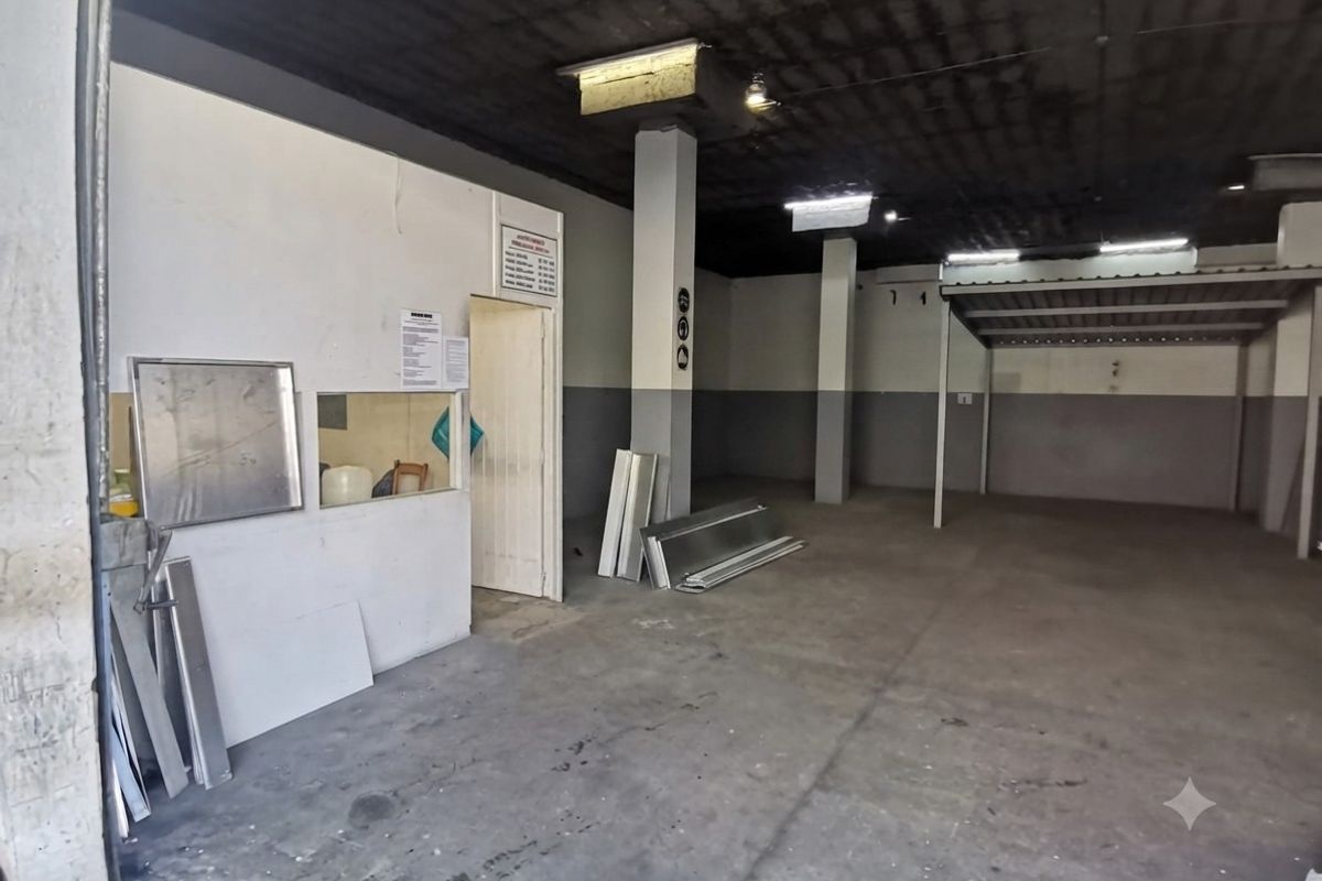 An open-plan industrial utility space featuring concrete flooring, structural columns, and exposed ceiling, suitable for workshop or storage use.