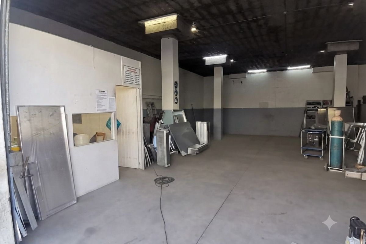 Spacious industrial utility area featuring concrete flooring, exposed ceiling, and structural columns, suitable for workshop or storage use.