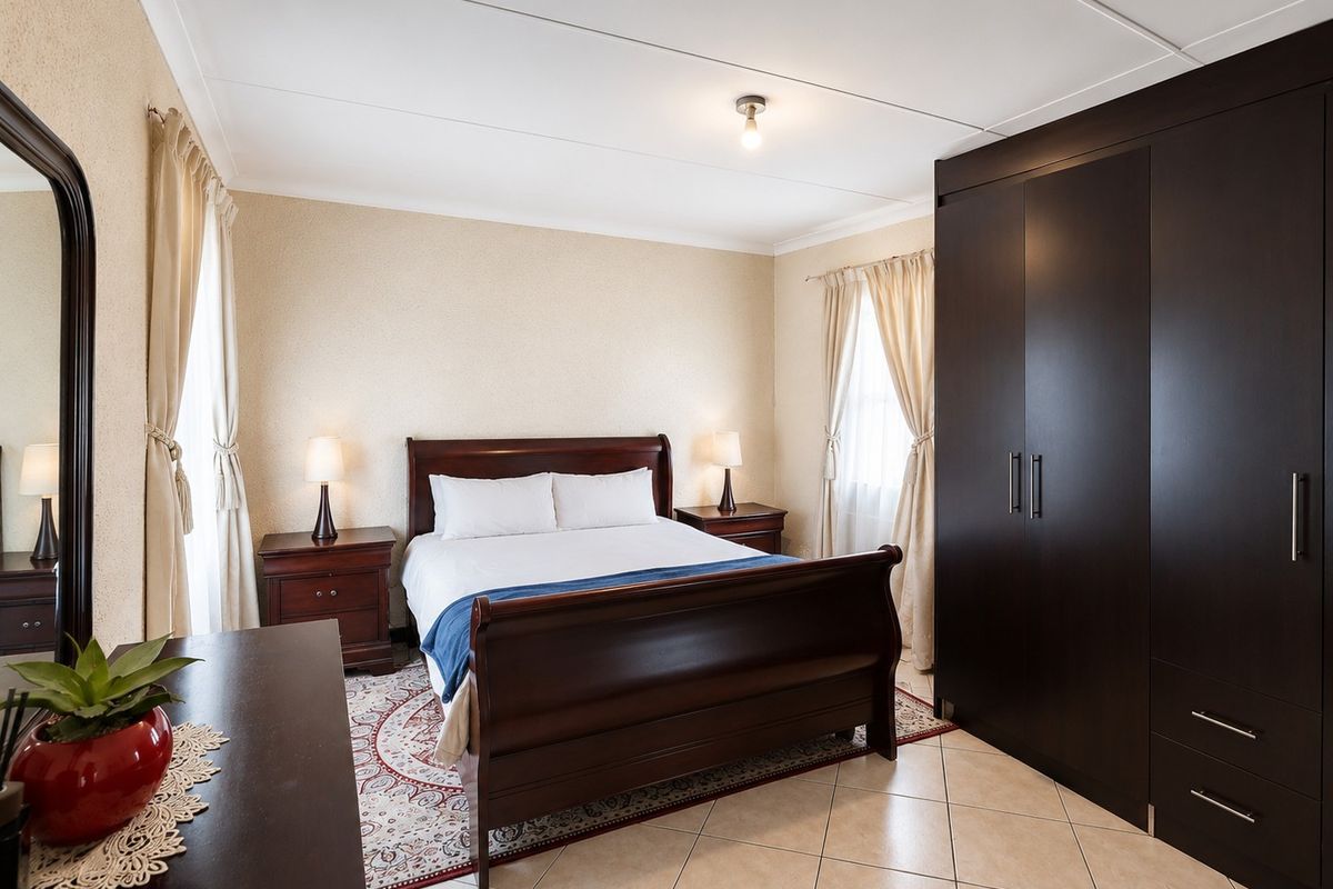 A well-maintained bedroom featuring tiled flooring and a large built-in dark wood wardrobe.