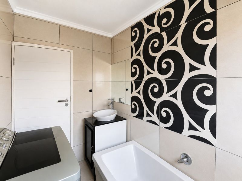 Modern bathroom featuring a vessel sink on a vanity, a bathtub, and striking black and white decorative wall tiles.