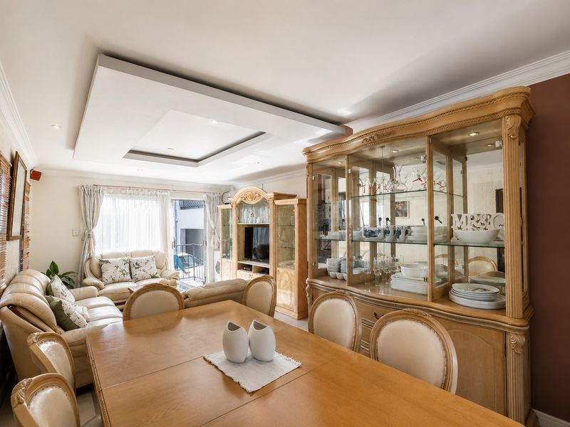 Open-plan living and dining area featuring a recessed ceiling with downlights and a sliding glass door leading to an outdoor space.