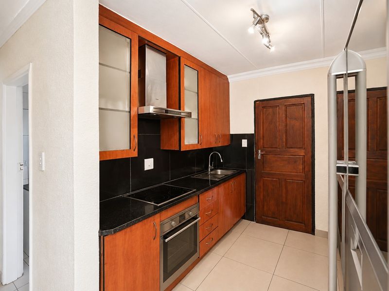 A functional kitchen featuring warm-toned wooden cabinetry, black granite countertops, integrated appliances, and tiled flooring.