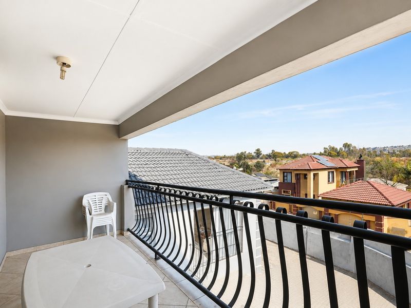 A covered balcony featuring tiled flooring and a decorative wrought iron balustrade, offering elevated views of the surrounding residential neighborhood.