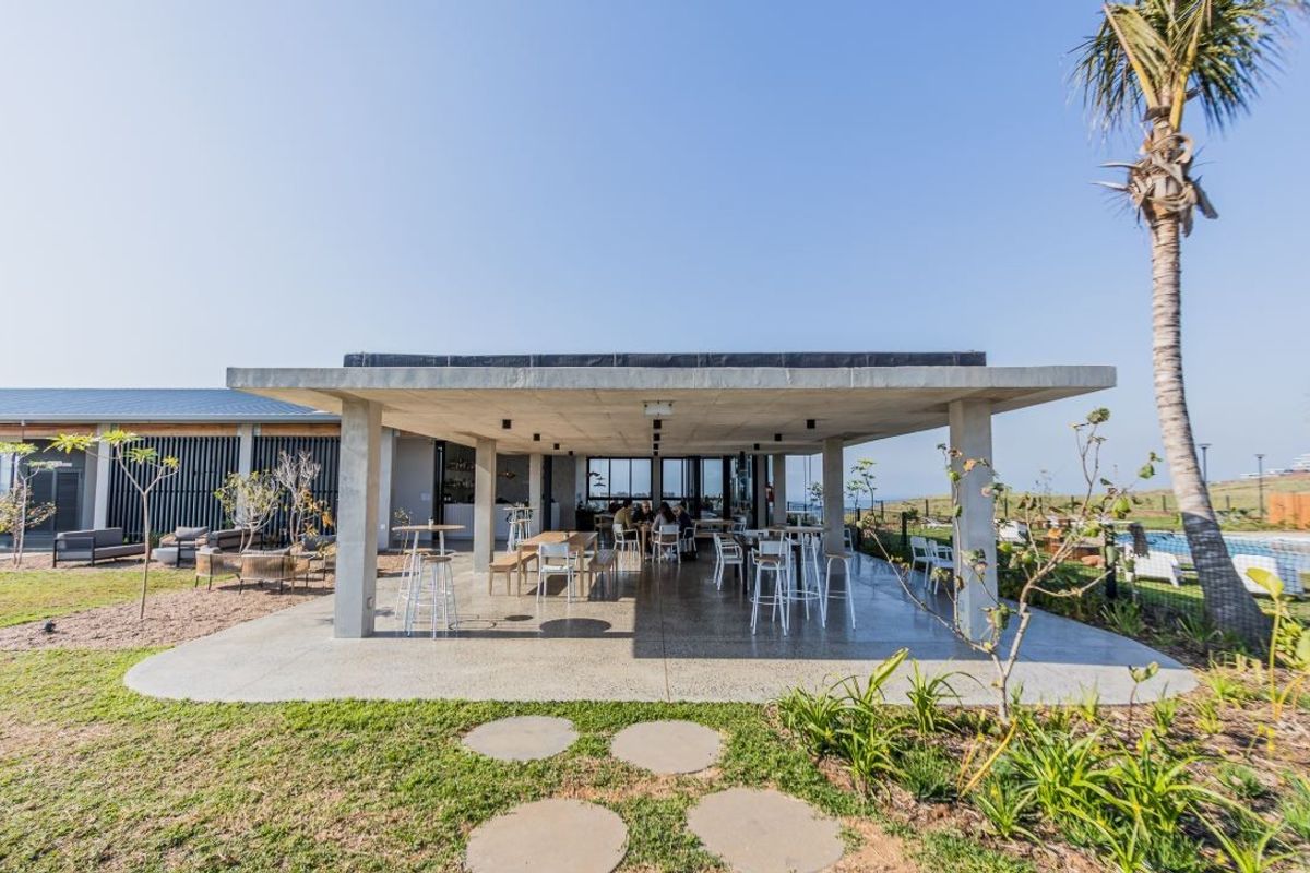 A spacious covered outdoor patio featuring a modern concrete structure, polished flooring, and recessed lighting, ideal for alfresco dining and entertaining.