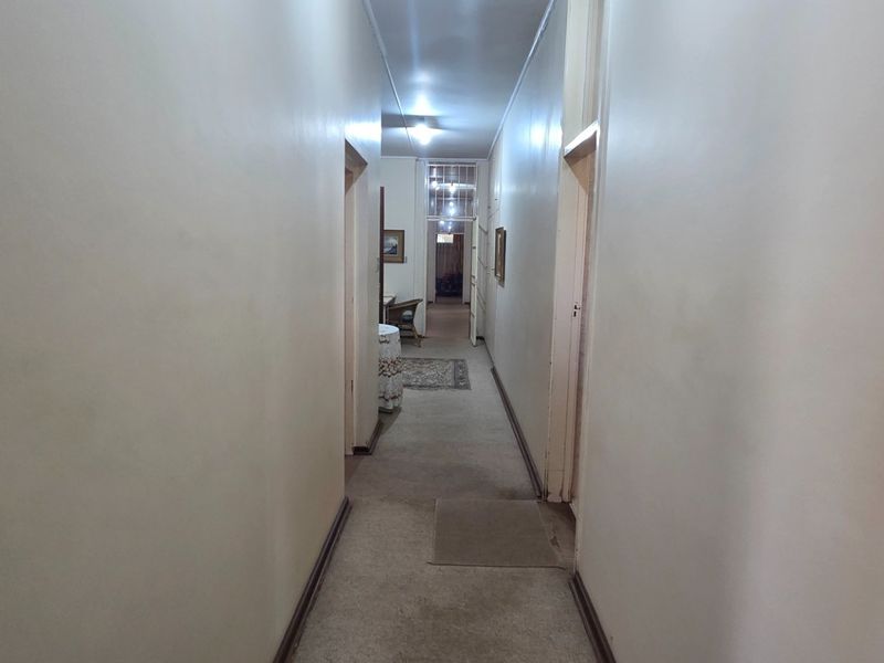 A long, neutral-toned hallway connecting multiple rooms, featuring carpeted flooring and standard internal door access.