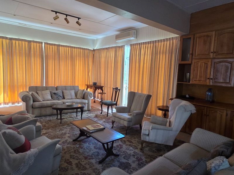 Spacious living room featuring built-in wooden cabinetry, a fireplace, and split-system air conditioning, offering a traditional layout with ample natural light.