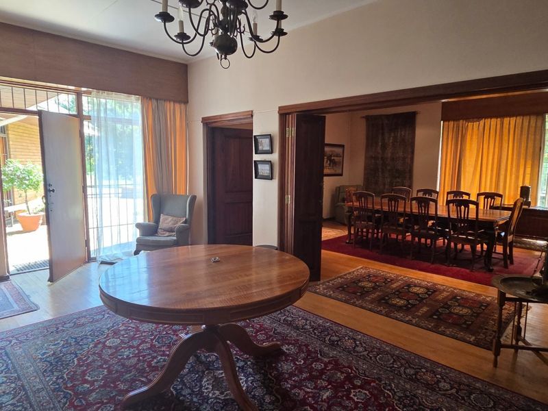 Spacious living area featuring hardwood flooring, classic wooden door frames, and a chandelier, with direct access to an outdoor patio area.