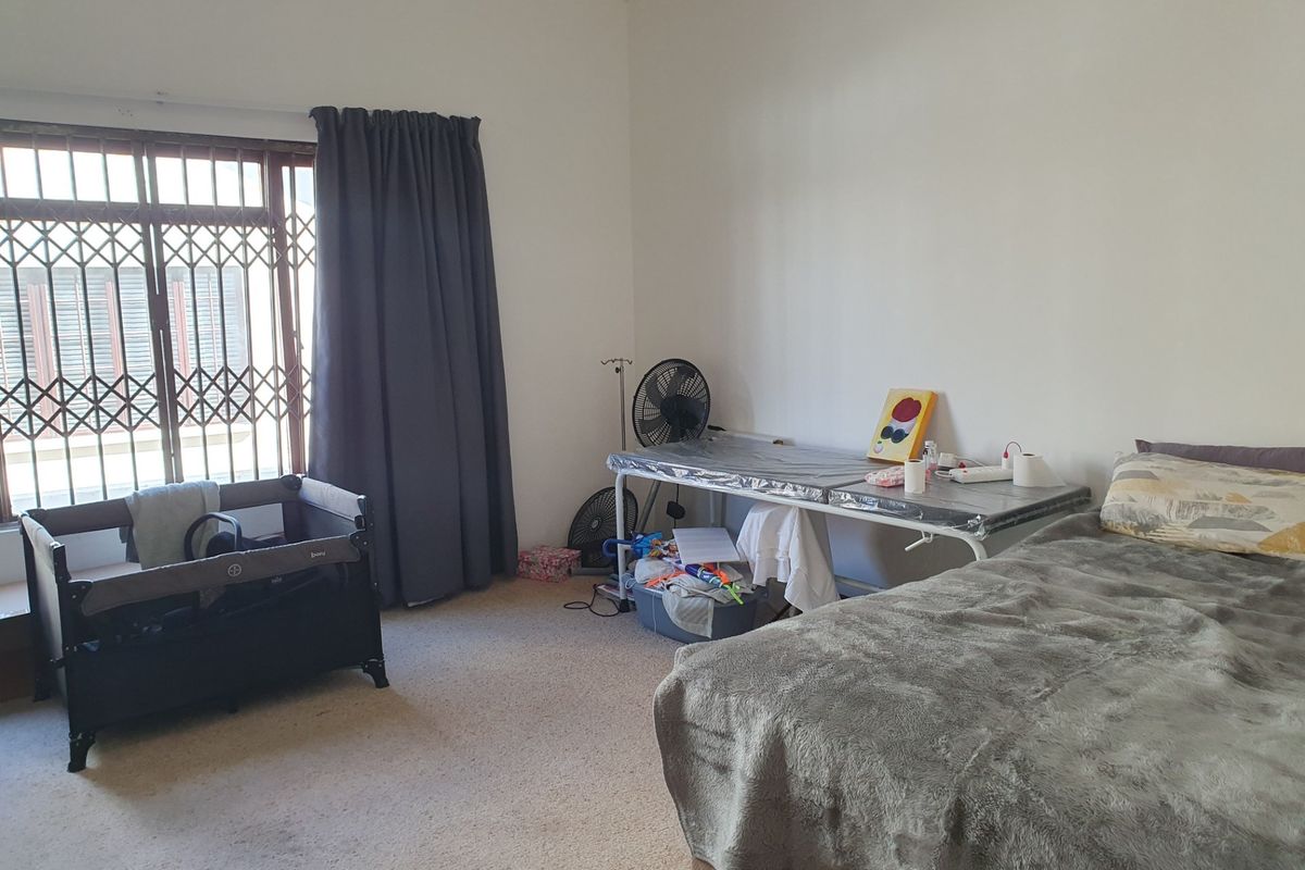 A spacious bedroom featuring carpeted flooring and a window fitted with a security gate, offering a neutral canvas for personalization.
