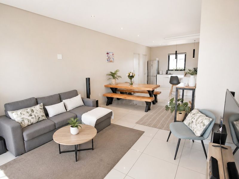 Spacious open-plan living and dining area featuring modern tiled flooring, recessed lighting, and a seamless flow into the contemporary kitchen space.
