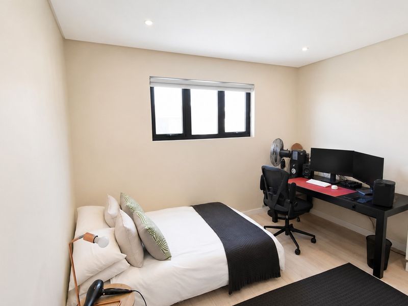 A well-maintained bedroom featuring neutral walls, laminate flooring, recessed downlights, and a built-in wardrobe.