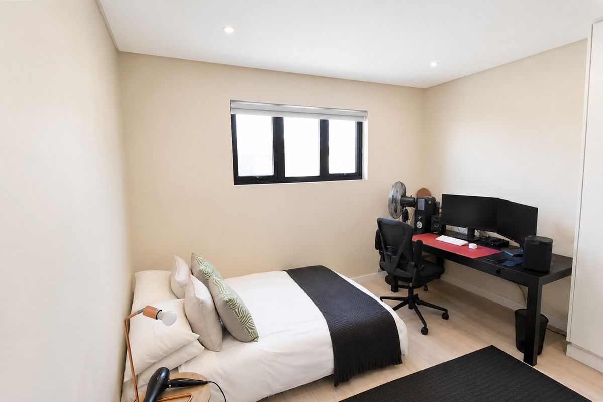 A well-maintained bedroom featuring neutral walls, laminate flooring, recessed downlights, and a built-in wardrobe.