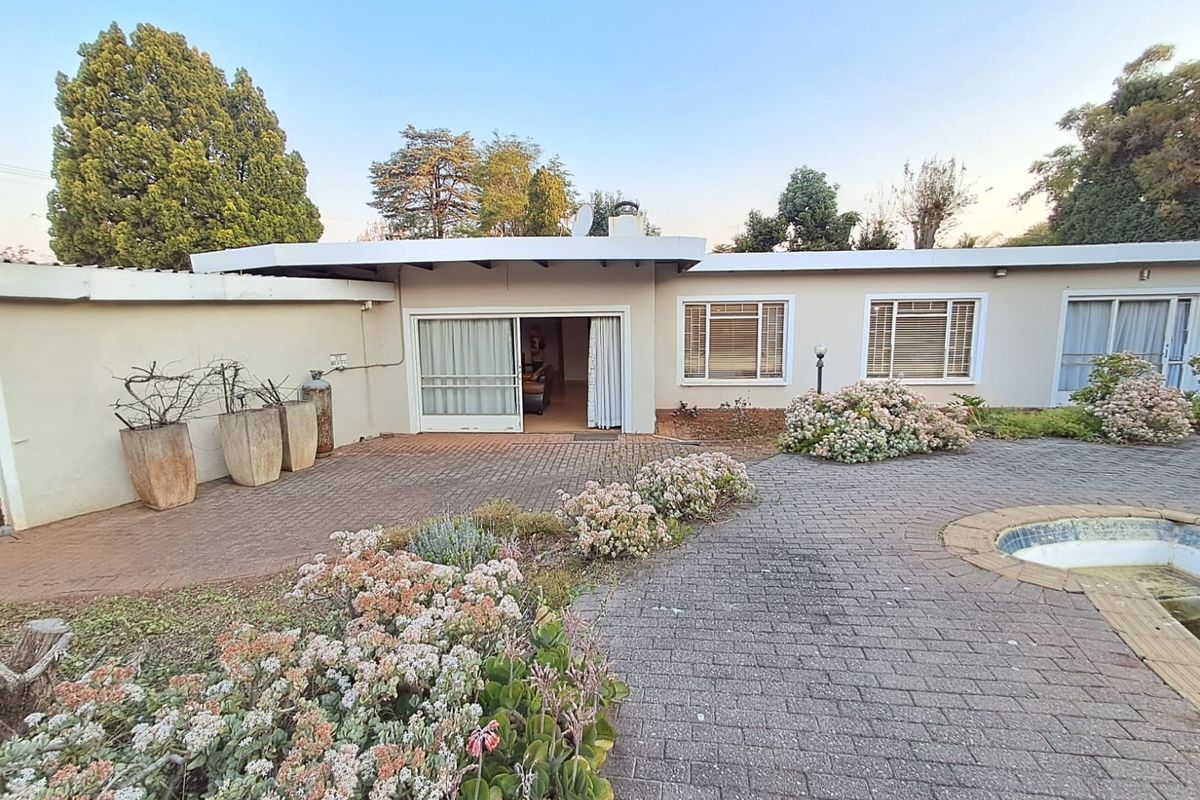 Rear exterior view of the house featuring a paved patio area, swimming pool, and direct access to the interior through sliding glass doors.