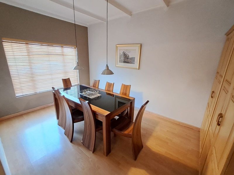 A well-maintained dining room featuring laminate flooring, pendant lighting, and built-in cabinetry, offering a clean and functional space for family meals.