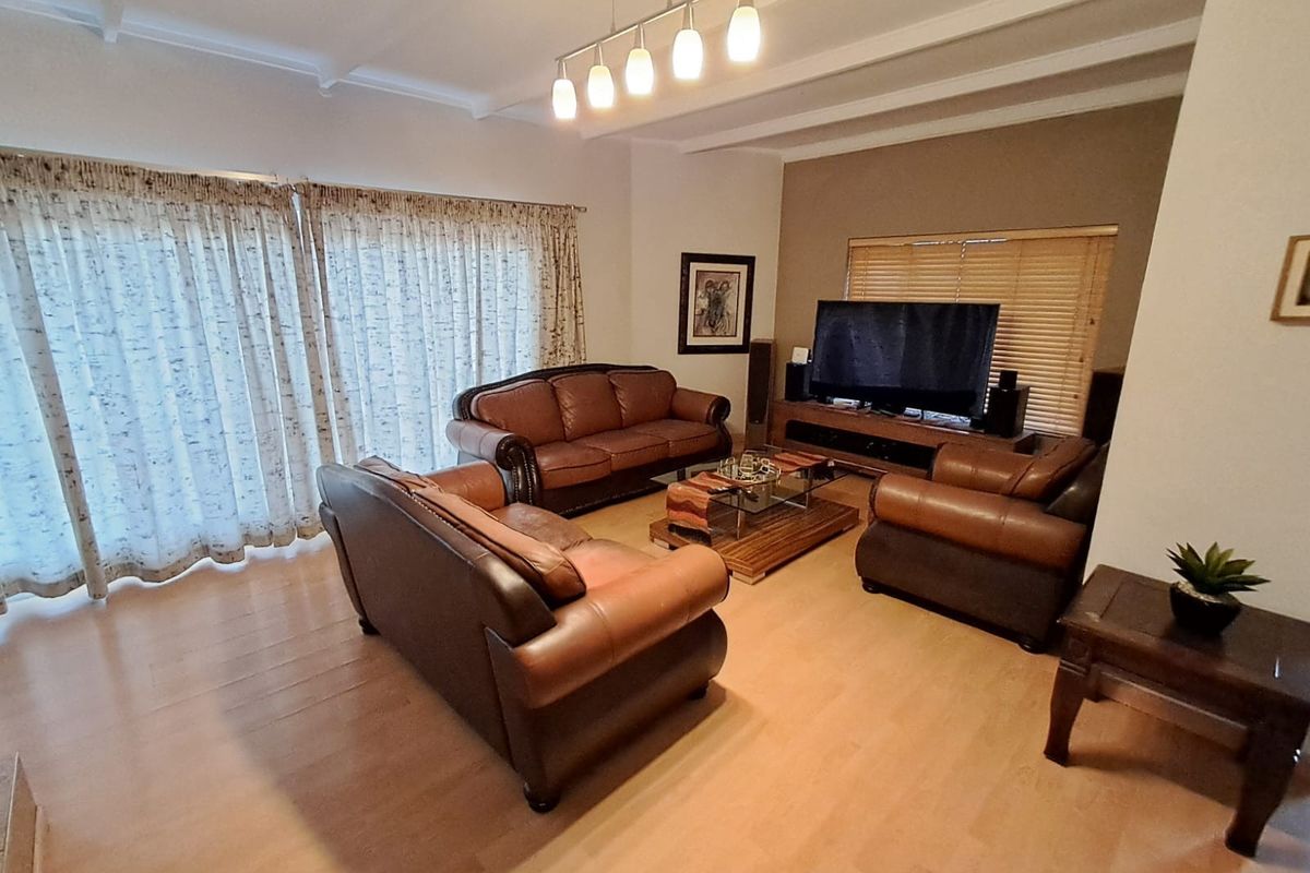 A spacious living room featuring laminate flooring, exposed beam ceilings, and large sliding glass doors that provide ample natural light.