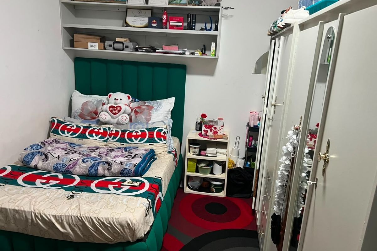 A compact bedroom featuring built-in shelving and a fitted wardrobe, providing functional storage space within the room.