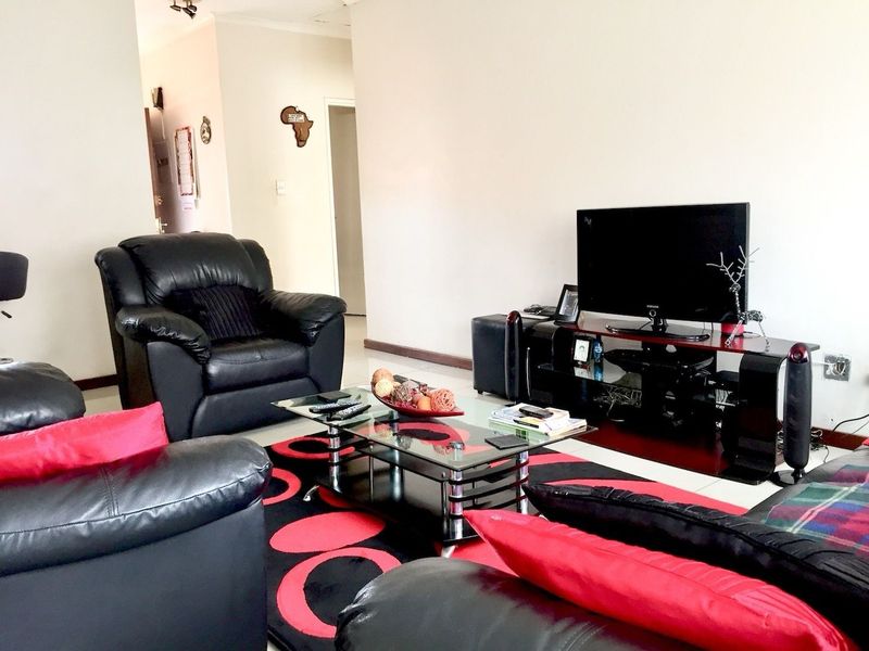 A living room area featuring neutral wall finishes and tiled flooring, providing a functional space for relaxation and entertainment.
