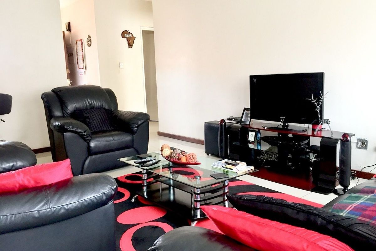 A living room area featuring neutral wall finishes and tiled flooring, providing a functional space for relaxation and entertainment.
