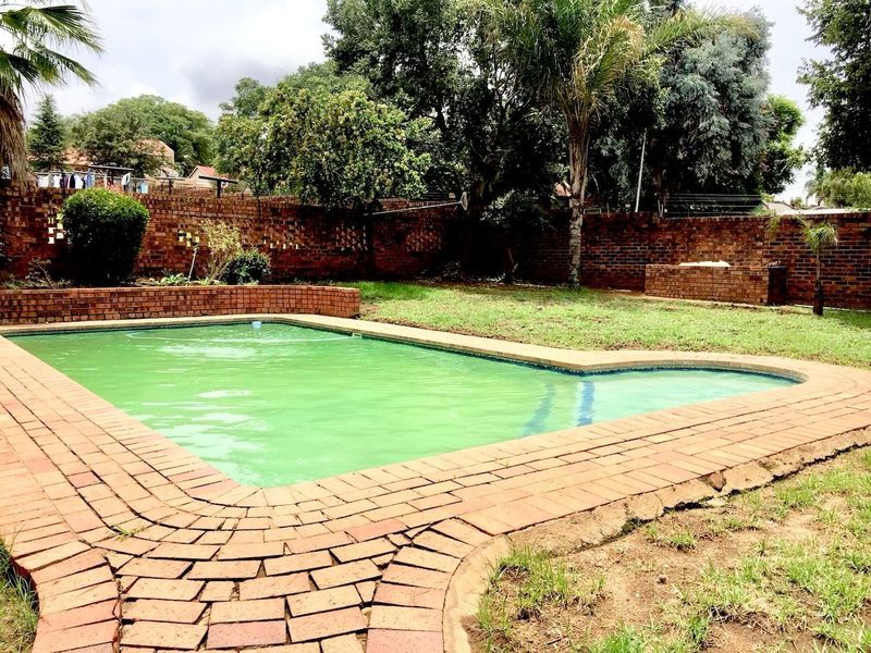 Outdoor pool area featuring a swimming pool with brick paving surround and a perimeter brick boundary wall.