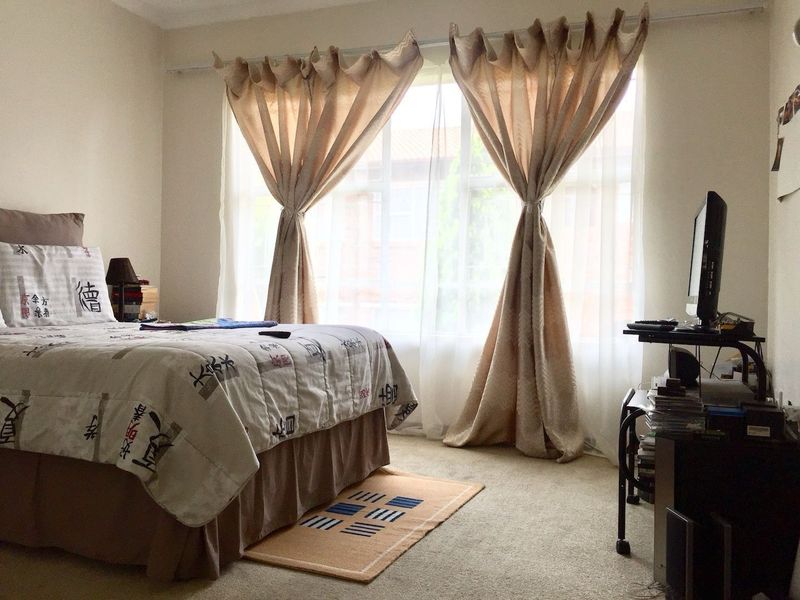 A standard bedroom featuring neutral wall tones, carpeted flooring, and a large window that provides natural light.