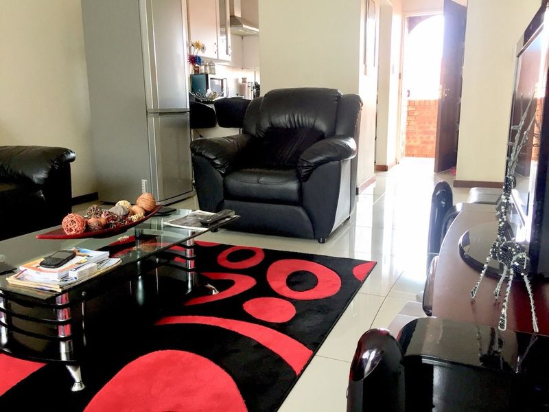 Open-plan living area featuring tiled flooring and a view into the adjacent kitchen space with built-in cabinetry.