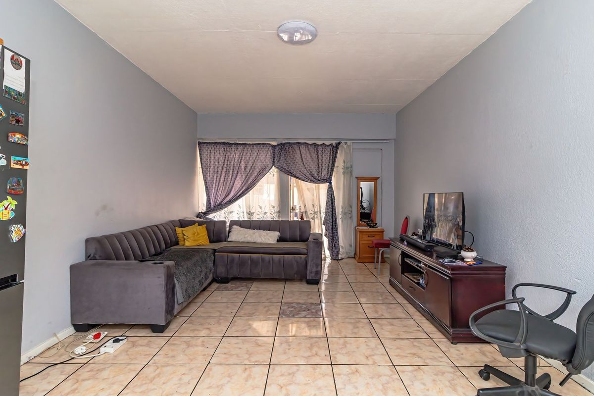 A living room featuring ceramic floor tiles and a sliding glass door providing natural light.