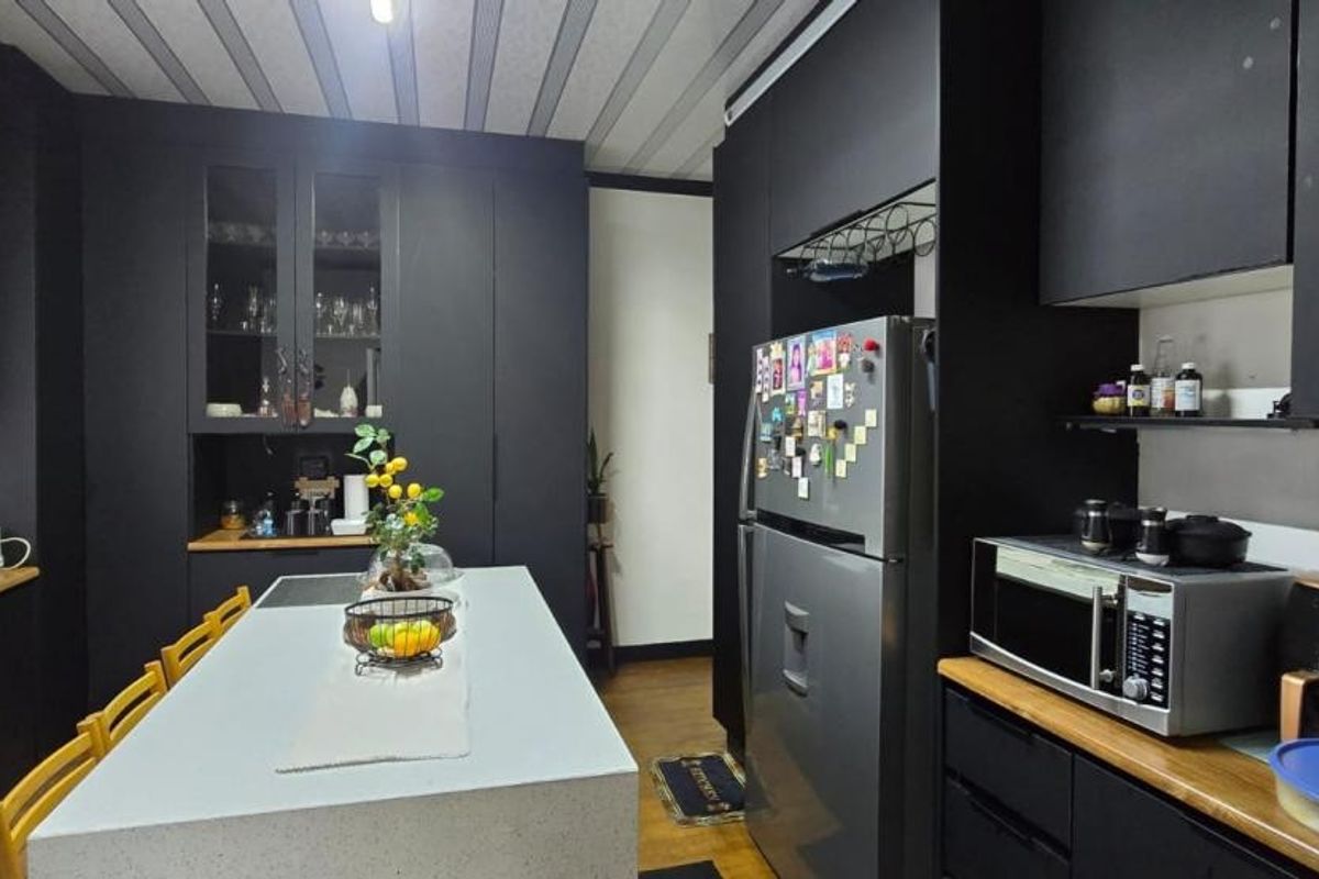 Modern kitchen featuring matte black cabinetry, a central island with a quartz countertop, and integrated storage solutions.