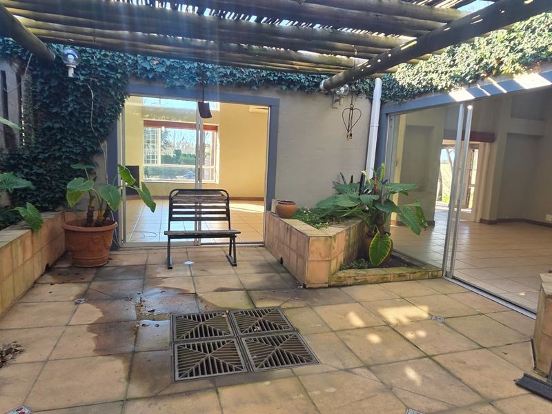 A private courtyard patio featuring a timber pergola, tiled flooring, and built-in planter boxes, with direct access to the interior living spaces.