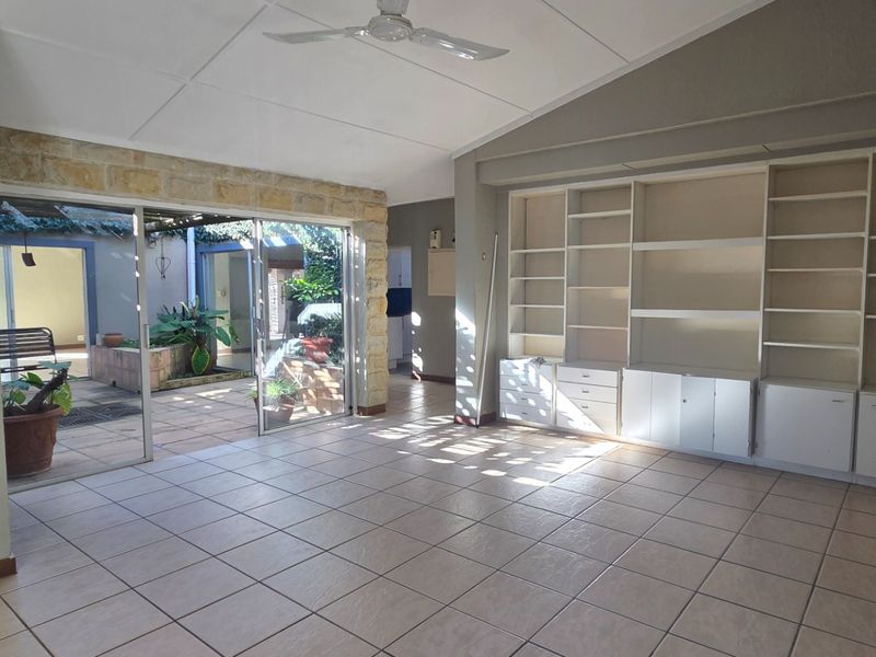 Spacious living area featuring built-in shelving, tiled flooring, and large sliding doors opening onto a private courtyard.