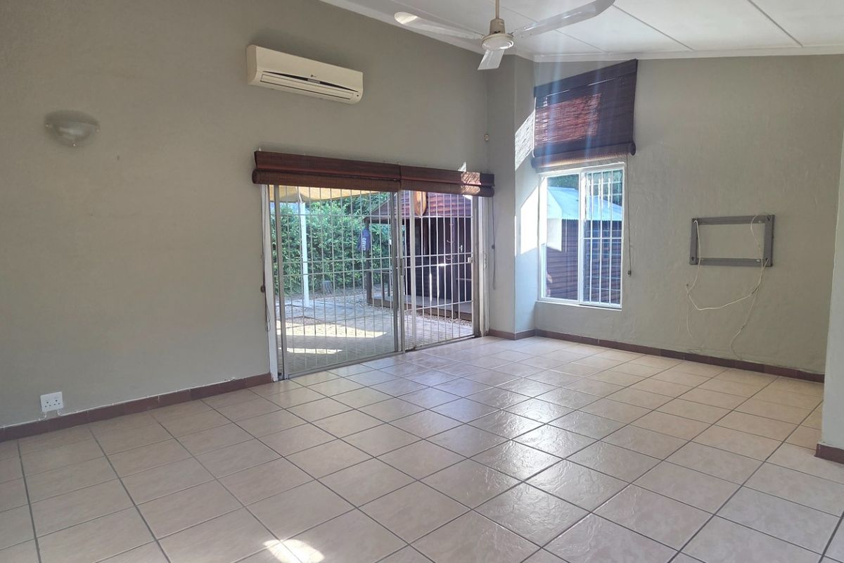 Spacious, empty living area featuring tiled floors, a ceiling fan, split-system air conditioning, and direct access to the outdoor area via sliding glass doors.