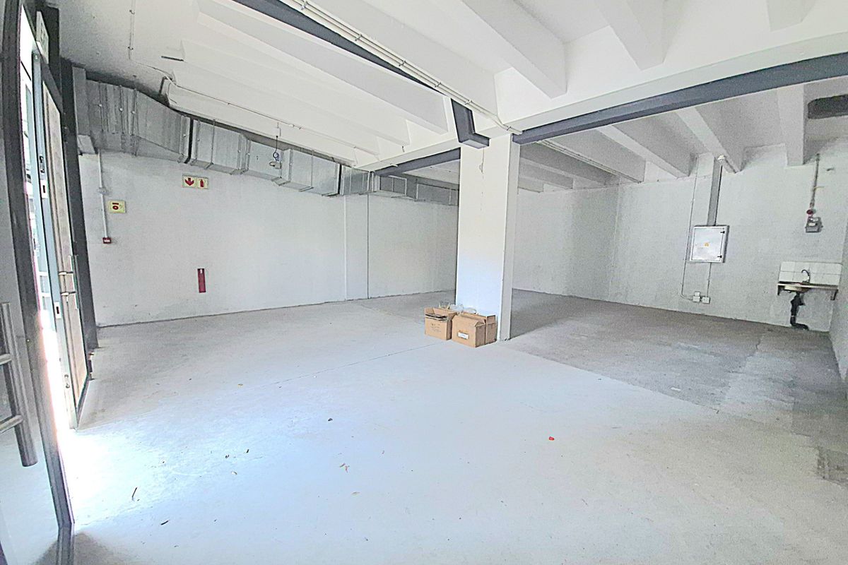 Open-plan retail space featuring exposed industrial ceilings, concrete flooring, a utility sink, and large glass entrance doors, suitable for various commercial fit-out options.