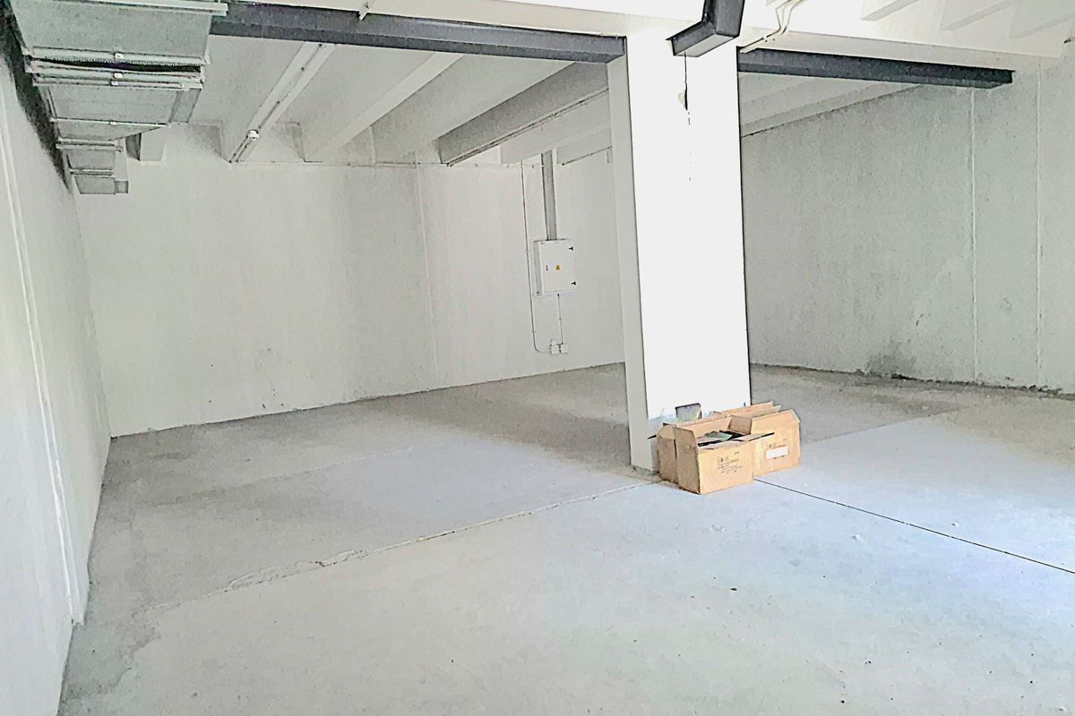 An open-plan utility or storage space featuring exposed ceiling beams, industrial ductwork, and concrete flooring, suitable for various commercial or storage applications.