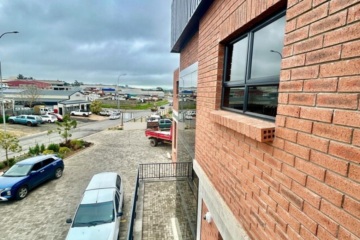 Elevated view of a modern commercial building featuring face brick exterior, aluminium windows, and a paved parking area.