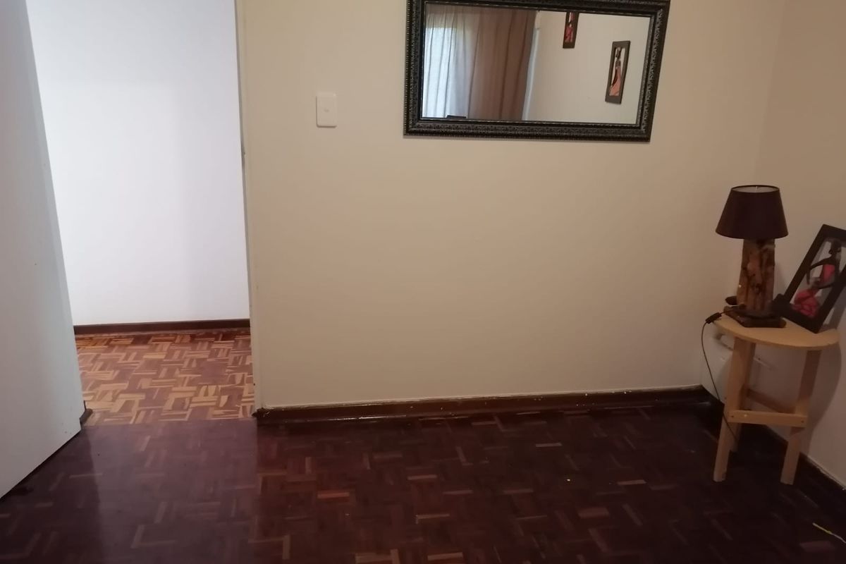 A bedroom featuring traditional parquet flooring and timber skirting boards, offering a neutral space ready for personalization.