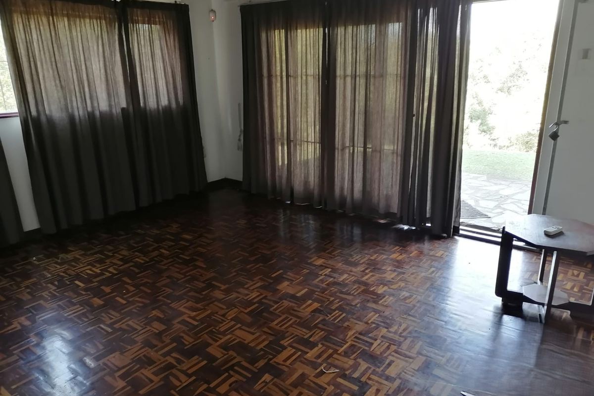 Spacious living room featuring traditional parquet flooring and large sliding glass doors providing direct access to the outdoor area.