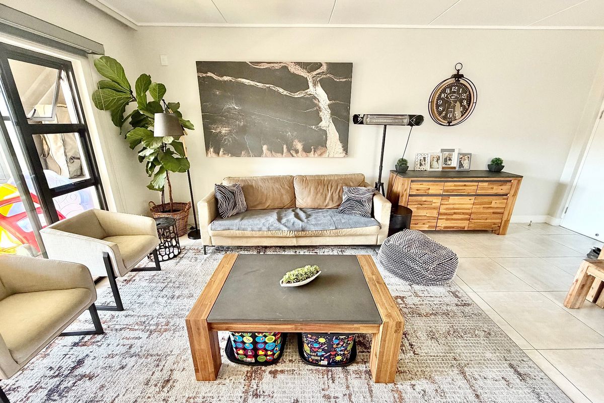 A bright and spacious living room featuring large format floor tiles and a sliding glass door providing access to the outdoor area.