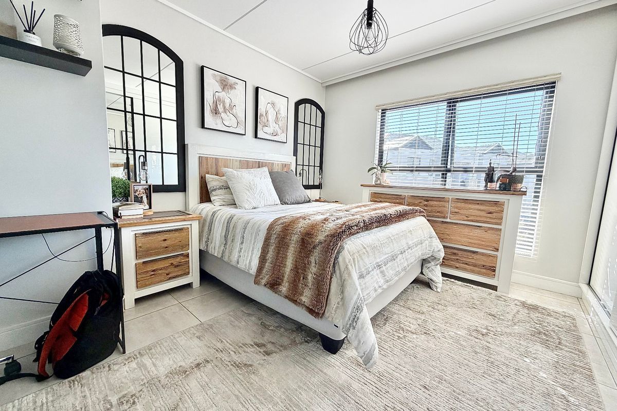 A well-maintained bedroom featuring tiled flooring, modern pendant lighting, and large windows fitted with venetian blinds.