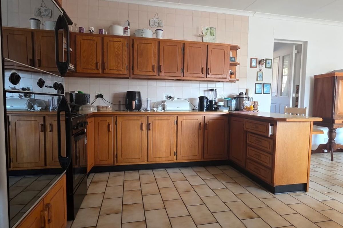 A functional kitchen featuring traditional wooden cabinetry, tiled backsplash, and tiled flooring, offering a classic layout with integrated oven and ample storage space.