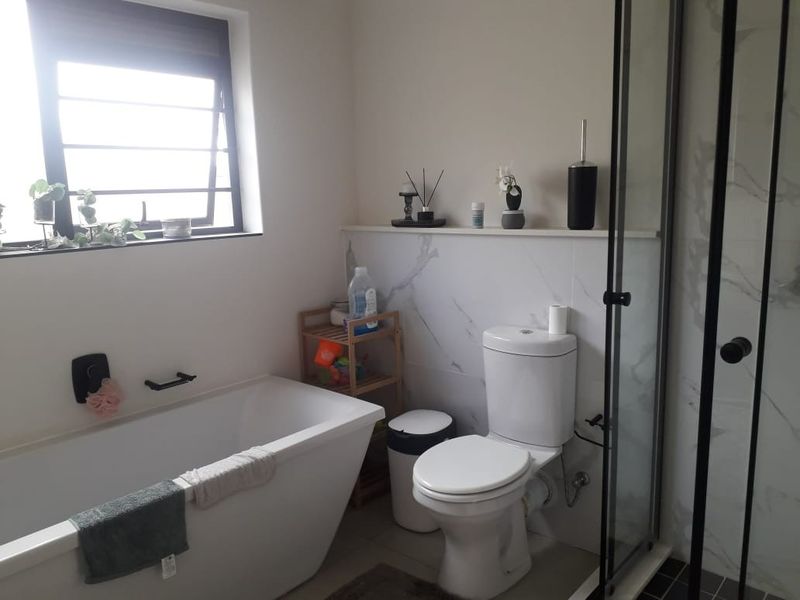 Modern bathroom featuring a freestanding bathtub, separate shower enclosure with black frame, and marble-look wall tiling.