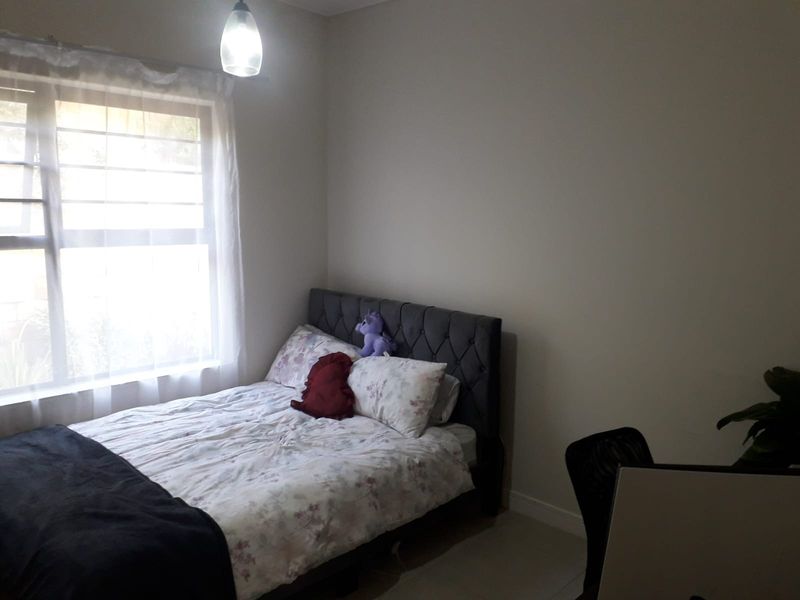 A bedroom featuring a window with security bars and a central pendant light fixture.