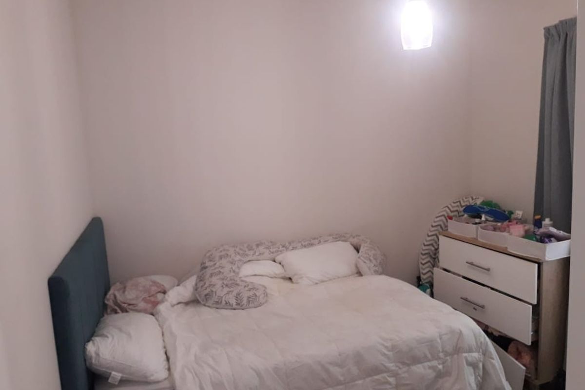 A standard bedroom featuring neutral wall finishes and a central pendant light fixture.