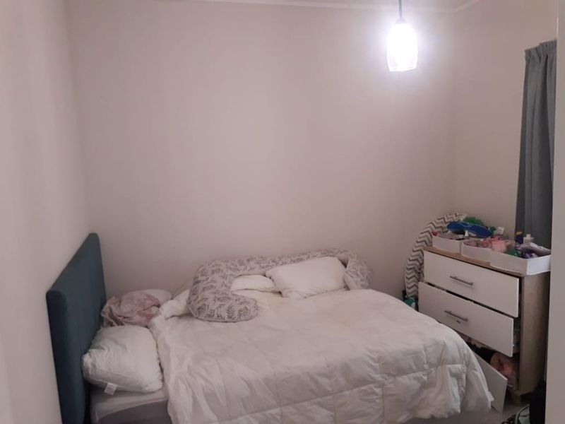 A standard bedroom featuring neutral wall finishes and a central pendant light fixture.