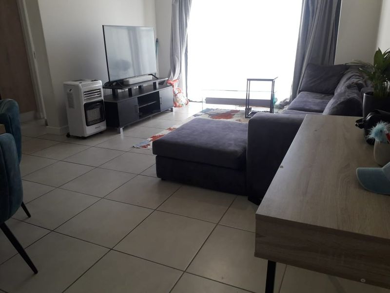 A living room area featuring neutral tiled flooring and a large sliding glass door providing natural light.