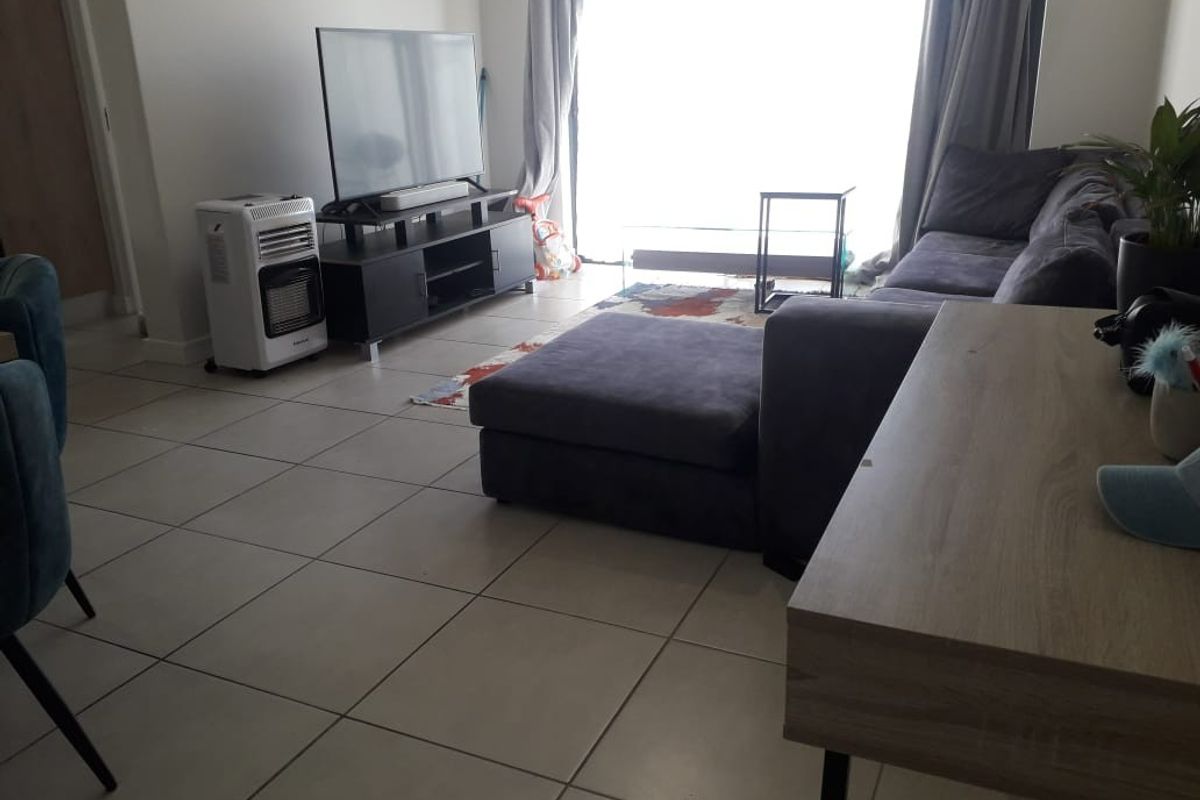 A living room area featuring neutral tiled flooring and a large sliding glass door providing natural light.