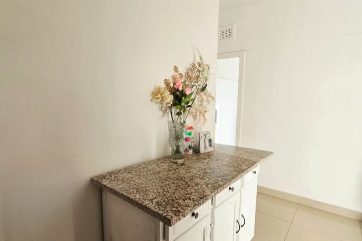 A hallway area featuring built-in cabinetry with a granite countertop and neutral tiled flooring.