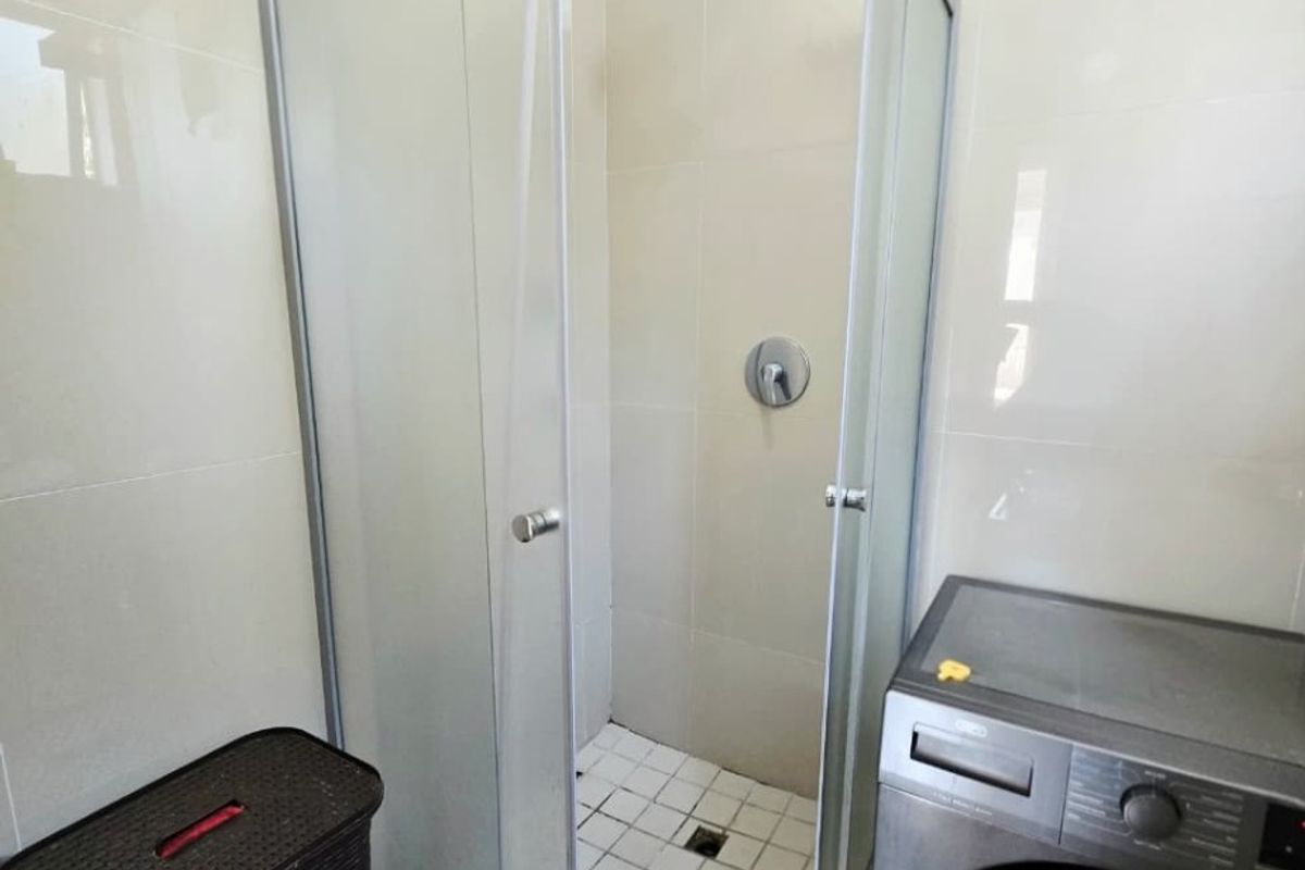A functional bathroom featuring a glass-enclosed shower with tiled walls and flooring, providing a clean and practical space.