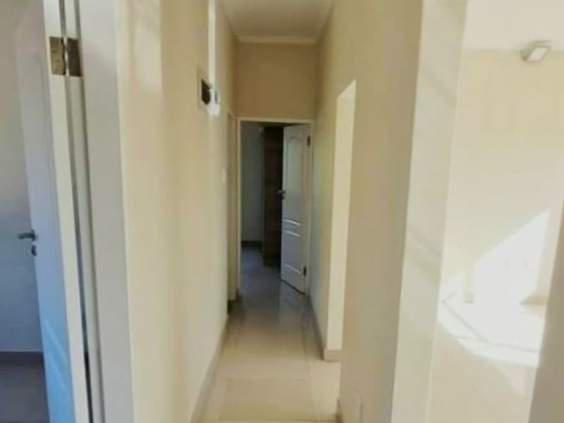 A clean, neutral-toned hallway featuring tiled flooring and access to multiple rooms within the apartment.