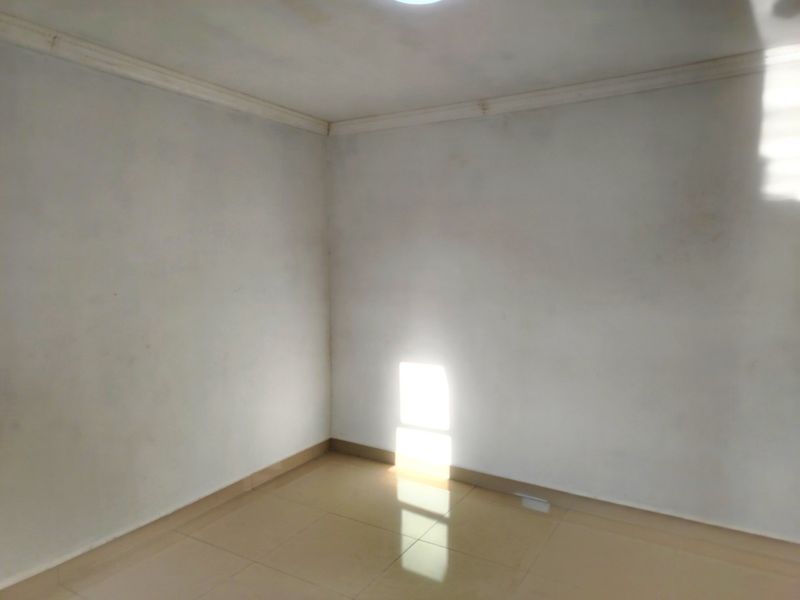 An empty bedroom featuring tiled flooring and ceiling cornicing, requiring cosmetic updates to the wall finishes.