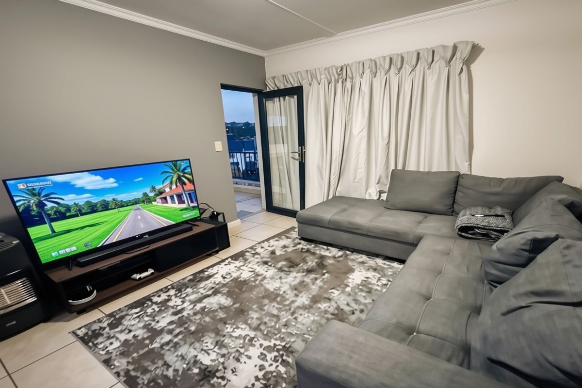 A comfortable living room featuring tiled flooring, crown molding, and direct access to an outdoor balcony through a glass sliding door.